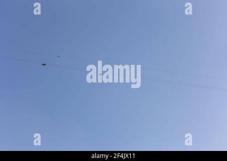 Jebel Jais Flight, die längste Zipline der Welt, Menschen in Gurtzeugen, die die Reißleine gegen den blauen Himmel hinuntergleiten, Blick von unten. Stockfoto