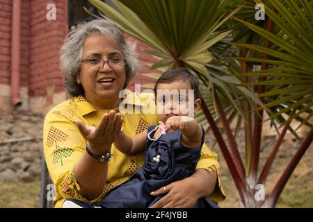 Glückliche Momente mit Oma, indische oder asiatische ältere Dame verbringen Zeit mit ihrer Enkelin im Garten. Stockfoto