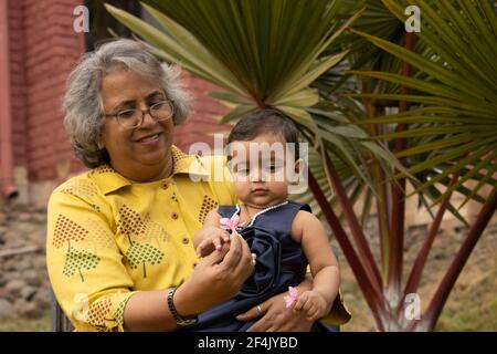 Glückliche Momente mit Oma, indische oder asiatische ältere Dame verbringen Zeit mit ihrer Enkelin im Garten. Stockfoto