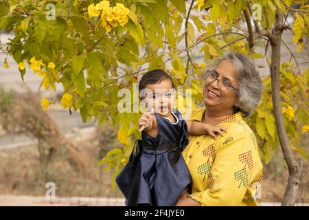 Glückliche Momente mit Oma, indische oder asiatische ältere Dame verbringen Zeit mit ihrer Enkelin im Garten. Stockfoto