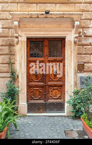 Antike schöne Holztür mit Türklopfer und Veranda mit Blumen in Italien, Rom dekoriert. Stockfoto