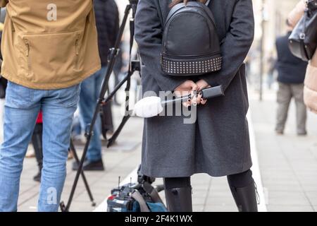 Weibliche Fernsehreporterin mit Mikrofon, die auf Medienereignis oder Pressekonferenz wartet. Jobkonzept Journalismus. Stockfoto