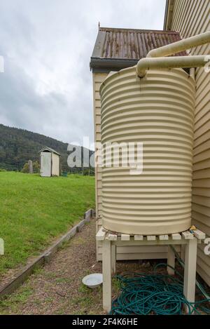 Ein Regenwassertank und eine Außentoilette im Hinterhof Hinten oder eine kleine Holzkirche in Central Tilba auf Die Südküste von New South Wales in Australien Stockfoto