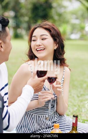 Glücklich aufgeregt junge asiatische Frau trinken Wein mit Freund in Stadtpark Stockfoto