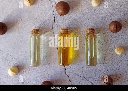 Nahaufnahme von natürlichem Macadamiaöl und Macadamianüssen auf Steinplatte. Gesundes Produkt. Stockfoto