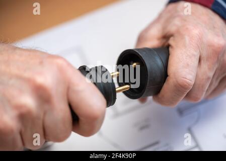 Elektroinstallateur hält Elektrostecker in der Hand Stockfoto