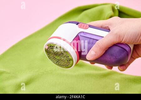 Ein Woman mit Fabric Shaver entfernt Stoffpillen von Kleidungsstücken. Nahaufnahme, selektiver Fokus Stockfoto