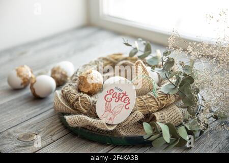 Osterstillleben mit verzierten Ostereiern und dekorativem Nest auf einer hölzernen Oberfläche. Frohe Ostern wünscht Konzept. Stockfoto