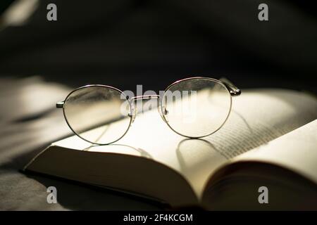 Weisheit und Wissen. Ein Buch lesen. Brillen auf einem Buch abgelegt. Stockfoto