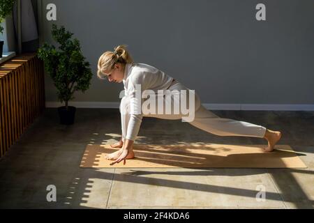 Eine Frau in weißer Sportbekleidung im Fitnessstudio auf der Matte trainiert. Stockfoto