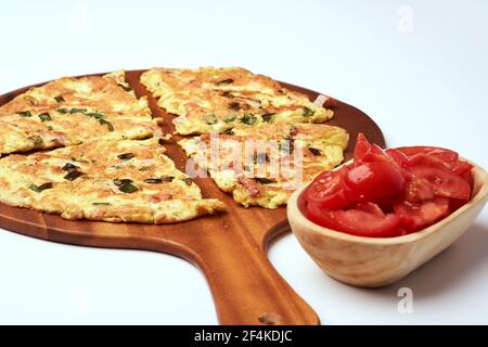Omelette mit Dill, Frühlingszwiebeln und Schinken auf einem Holzteller serviert, isoliert auf weißem Hintergrund Stockfoto