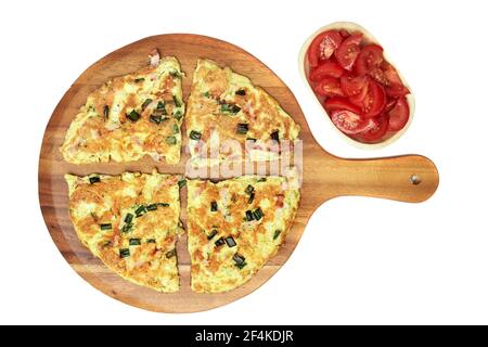 Omelette mit Dill, Frühlingszwiebeln und Schinken auf einem Holzteller serviert, isoliert auf weißem Hintergrund Stockfoto
