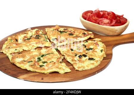 Omelette mit Dill, Frühlingszwiebeln und Schinken auf einem Holzteller serviert, isoliert auf weißem Hintergrund Stockfoto