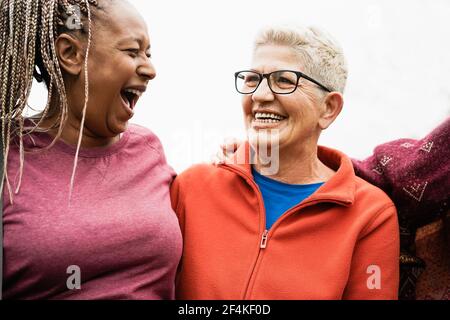 Glückliche ältere Frauen aus verschiedenen Ethnien lachen gemeinsam im Freien - Multirassische reife Freunde mit Spaß - fröhliche ältere Lebensstil - Konzentrieren Sie sich auf Stockfoto