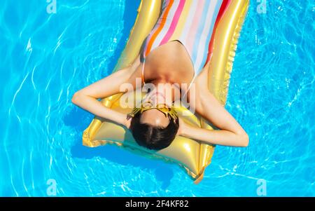 Draufsicht auf junge Frau im Swimmingpool im Freien auf schwimmenden Bett, entspannend. Stockfoto
