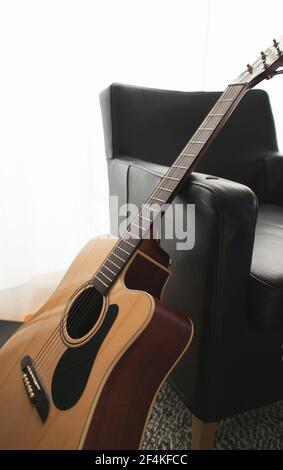 Eine akustische Gitarre auf einem Stuhl im Wohnzimmer gestützt. Stockfoto