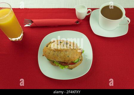 Hamburger auf einem weißen Teller und Orangensaft. Appetitliches Sandwich auf einem Teller als Hintergrund mit Platz für Text Stockfoto