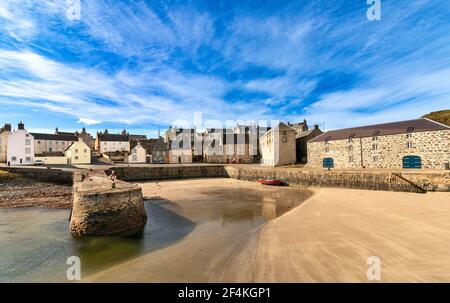 PORTSOY ALTER HAFEN MORAY FIRTH ABERDEENSHIRE SCHOTTLAND ALTE LAGERHÄUSER A SANDSTRAND BEI EBBE UND EIN ROTES BOOT Stockfoto