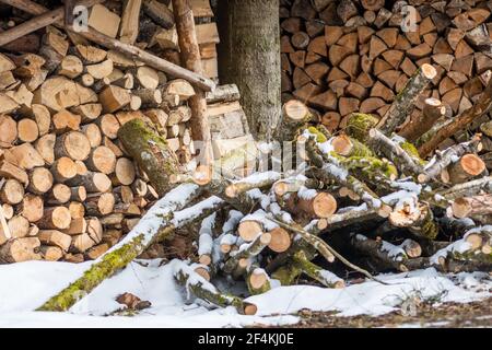 Stapel oder Stapel aus Blöcken, Stücken oder Holzstämmen im Winter oder Frühjahr mit Schnee. Stapelholz zum Trocknen und Lagern Stockfoto