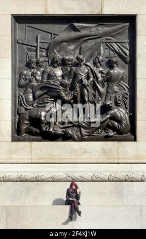 London, England, Großbritannien. Trafalgar Square - junge Frau sitzt auf der Basis von Nelson's Column unter dem Relief "die Schlacht von Cape St. Vincent" (Musgrave Stockfoto