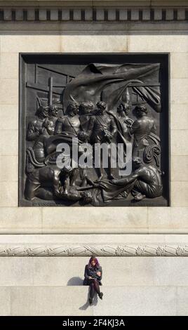 London, England, Großbritannien. Trafalgar Square - junge Frau sitzt auf der Basis von Nelson's Column unter dem Relief "die Schlacht von Cape St. Vincent" (Musgrave Stockfoto