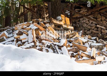 Stapel oder Stapel aus Blöcken, Stücken oder Holzstämmen im Winter oder Frühjahr mit Schnee. Stapelholz zum Trocknen und Lagern Stockfoto