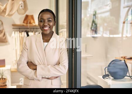 Lächelnde afroamerikanische Unternehmerin, die vor ihrem Geschäft steht Stockfoto