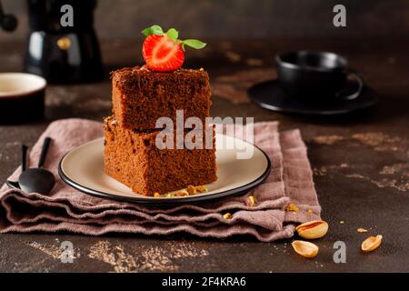 Stapel von Stücken oder Tafel Schokolade Kuchen Brownie mit Erdbeeren und Pistazien Nüsse auf dem schwarzen Hintergrund, selektive Fokus Bild Stockfoto