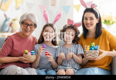 Schönen Urlaub! Mutter und ihre Töchter mit dem Malen von Eiern. Familie feiert Ostern. Nette kleine Kinder Mädchen tragen Hase Ohren. Stockfoto