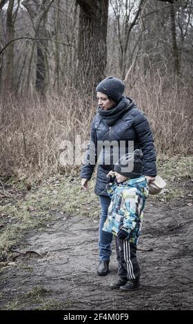 POZNAN, POLEN - 18. Feb 2018: Unbekannte Frau, die an einem kalten Wintertag eine Tasche mit Brot neben einem Kleinkind in einem Wald hält Stockfoto