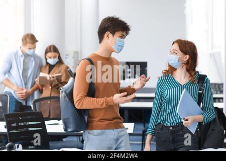 Asiatische Kerl und Rotschopf Frau trägt medizinische Masken und sprechen Stockfoto