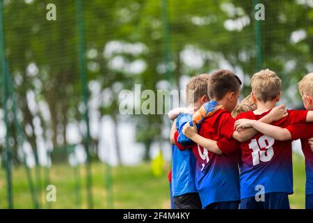 Happy Children huddling in einem Team auf Sportplatz. Gruppe von Schuljungen, die zusammen in einem Kreis stehen und sich vor dem Fußballspiel motivieren Stockfoto