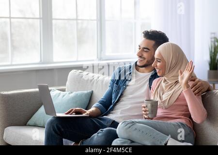 Glücklicher Mann und Frau winken auf Laptop-Bildschirm Stockfoto