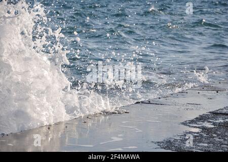 Wellen mit Spritzern auf felsigen Ufer. Wellen krachen an einer felsigen Küste der Golfküste. Stockfoto