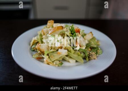 Ein caesar Salat in einem weißen Teller in der Küche Stockfoto