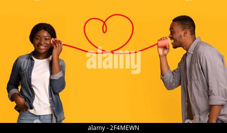 Liebevoll schwarz Kerl flüsterinf Worte der Liebe zu Freundin via Tin-Telefon Stockfoto