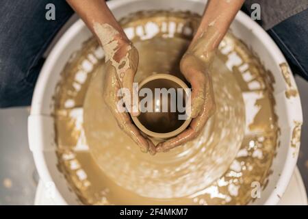 Stock Foto von nicht erkannten Person mit Töpferrad während der Töpferklasse. Stockfoto