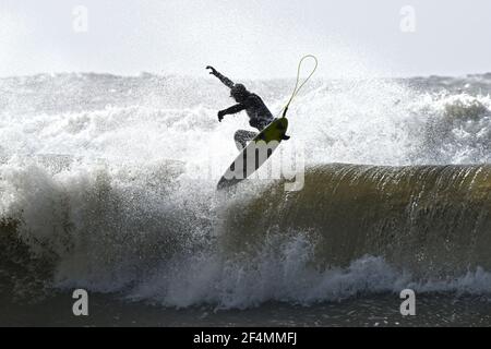 Surfer fliegt von der Spitze der Welle in einer Luftdrehung, die höchste Geschwindigkeit, Agilität und Wagemut erfordert. Stockfoto