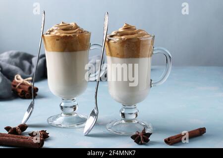 Dalgona cremiger Kaffee in zwei Gläsern auf blauem Hintergrund mit Schlagschaum. Koreanischer Kaffeetrend Stockfoto