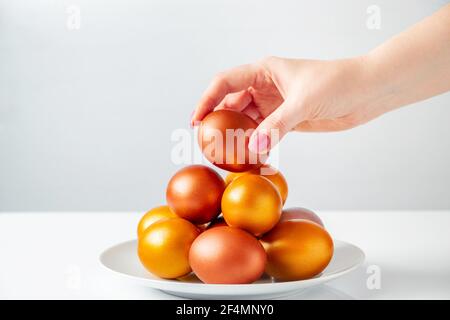 Frau legt goldenes Osterei in Stapel. Happy Holiday Konzept. Stockfoto