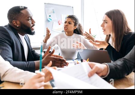 Zornige Geschäftspartner sitzen im Büro bei Verhandlungen, können nicht zu einer Einigung kommen. Multiethnische Kollegen argumentieren, sich gegenseitig die Schuld geben, scheiterten an einem Startup-Konzept, erfolglos Stockfoto