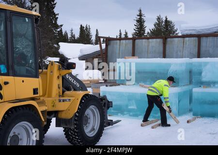 Der Mensch stapelt rechteckig geschnittenen Eisblock aus einem gefrorenen See Wir mussten das Ice Hotel in Jukkasjarvi in Schweden bauen Mit einem Lader Stockfoto