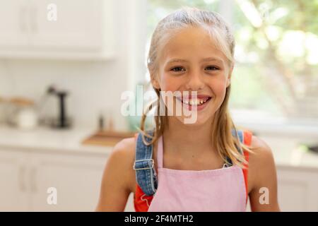 Porträt eines lächelnden kaukasischen Mädchens mit Schürze in der Küche Stockfoto