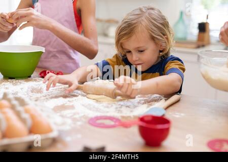 Kaukasischer Junge in der Küche Teig Rollen mit Schwester, tragen Schürzen backen Cookies zusammen Stockfoto