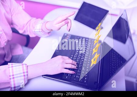 Eine Frau klickt auf eine Gold 5 fünf Sterne Bewertung mit Schreiben Online-Bewertung und Feedback, das Konzept einer positiven Bewertung, Reputationsmanagement und custo Stockfoto