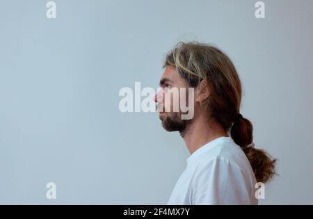 Seitenansicht eines spanischen fröhlichen jungen bärtigen Mannes in Ein weißes T-Shirt auf weißem Hintergrund Stockfoto