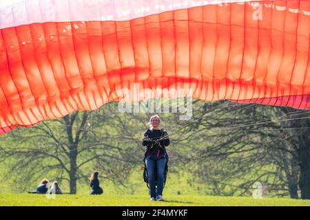 Die Gleitschirmfliegerin Karen praktiziert im Brockwell Park im Süden Londons, während die Menschen das warme Frühlingswetter genießen. Bilddatum: Montag, 22. März 2021. Stockfoto