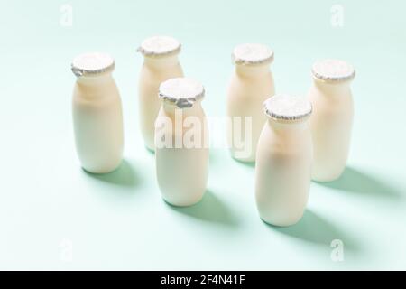 Kleine Flaschen mit Probiotika und Präbiotika Milchgetränk auf blauem Hintergrund. Herstellung mit biologisch aktiven Zusatzstoffen. Fermentation und Ernährung heilen Stockfoto