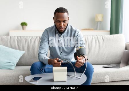 African American Young Man Messung Arterieller Blutdruck Zu Hause Stockfoto