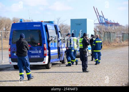 Hamburg, Deutschland. März 2021, 22nd. Polizeibeamte und Mitarbeiter des Technischen Hilfswerks (THW) stehen auf einer Öde im Hafen. Die Hamburger Polizei suchte mit einem großen Kontingent nach einem möglicherweise verletzten Autofahrer, der vor einer Verkehrskontrolle geflohen war und daraufhin einen Unfall verursachte. Quelle: Jonas Walzberg/dpa/Alamy Live News Stockfoto